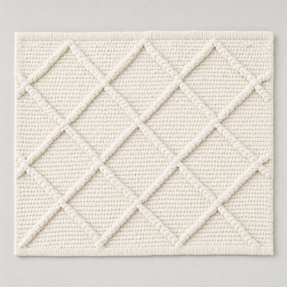 Deep Diamond Mat in milk white: a hand-woven cotton bath mat with a deep knotted diamond lattice in relief