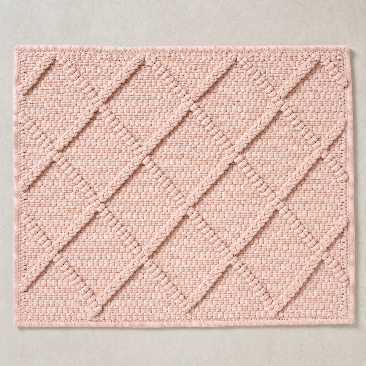 Deep Diamond Mat in pale pink: a hand-woven cotton bath mat with a deep knotted diamond lattice standing proud of the woven ground