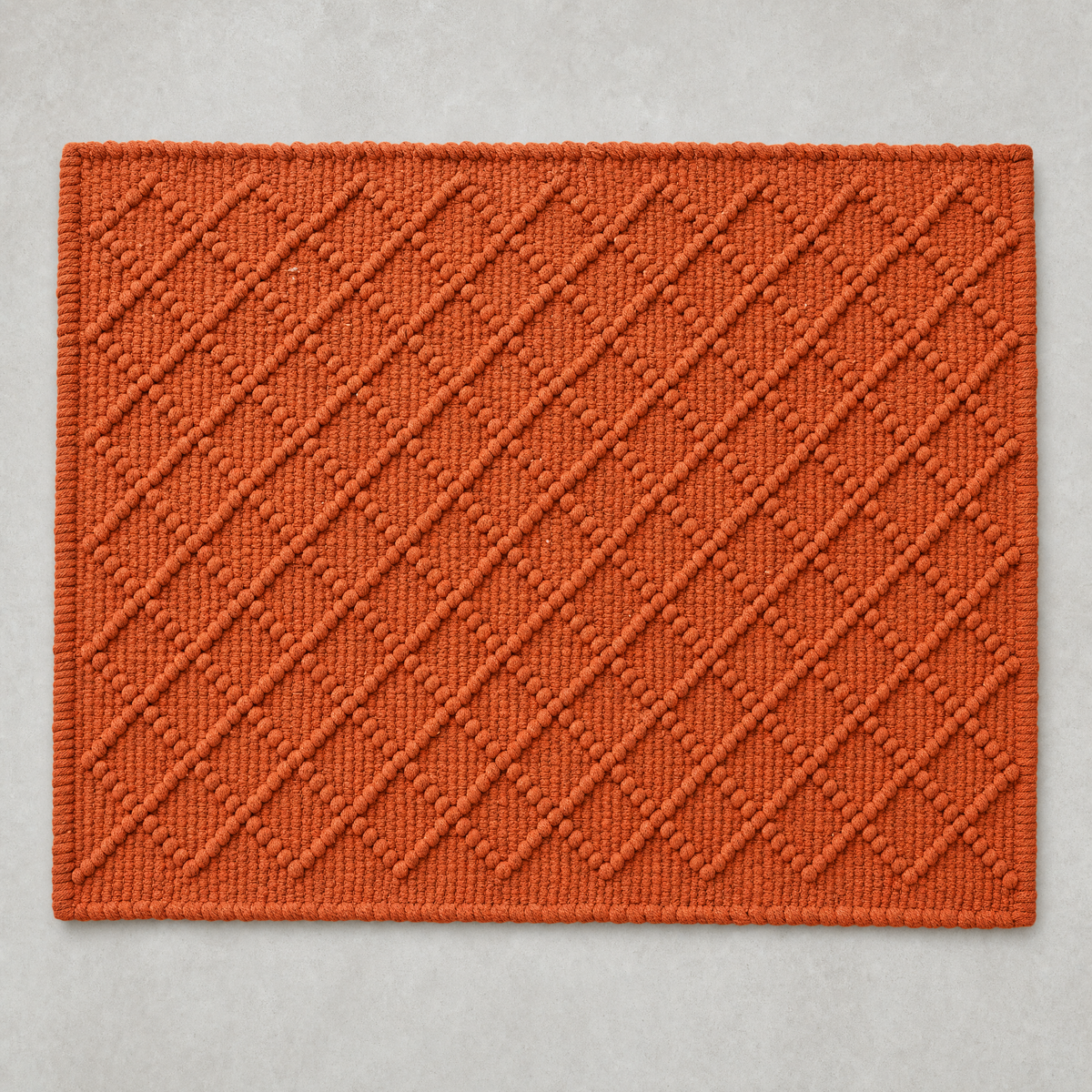 Diamond Mat in seville orange: a hand-woven cotton bath mat with a close knotted diamond weave