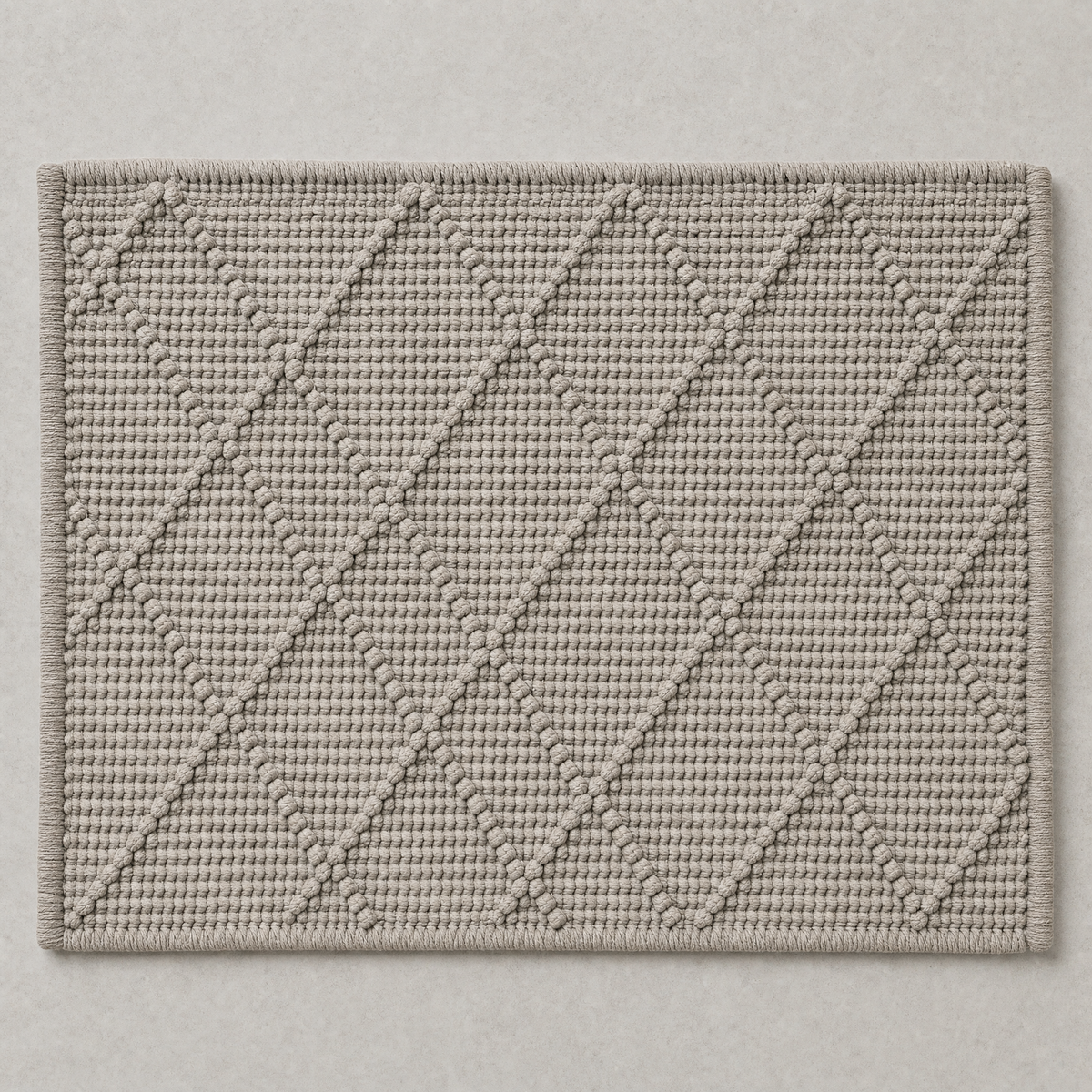 Diamond Mat in stone grey: a hand-woven cotton bath mat with a close knotted diamond weave