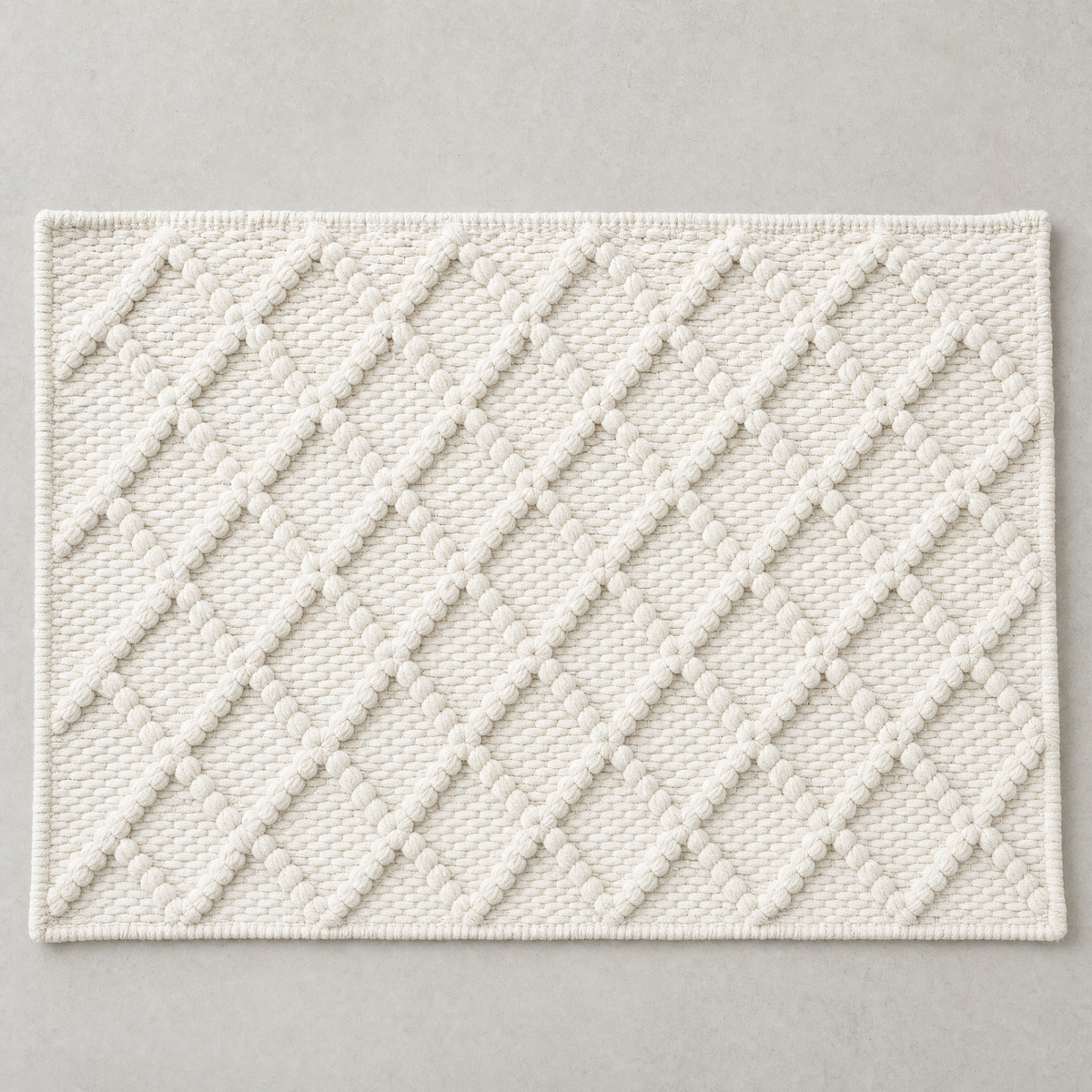 Diamond Mat in warm white: a hand-woven cotton bath mat with a close knotted diamond weave