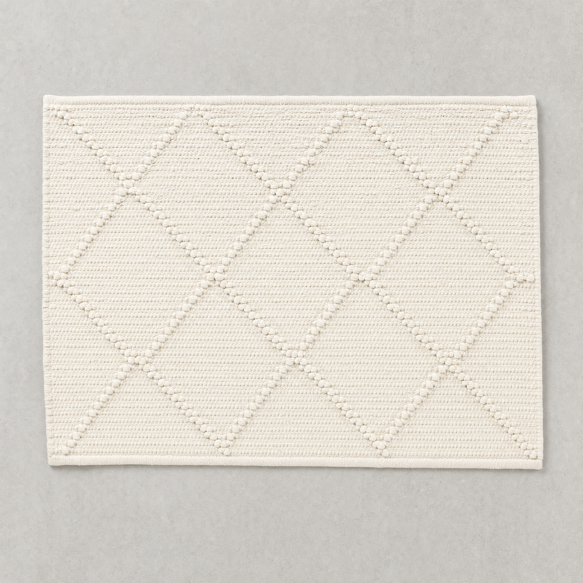 Open Diamond Mat in warm white: knotted diamond outlines over a flat woven cotton ground